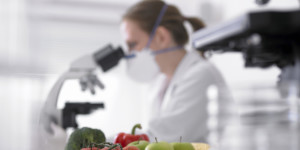 Fruits and vegetables next to scientist using microscope